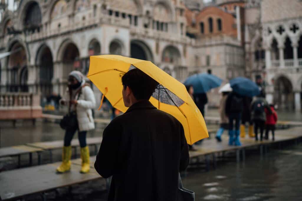 people with umbrellas in flooded Venice