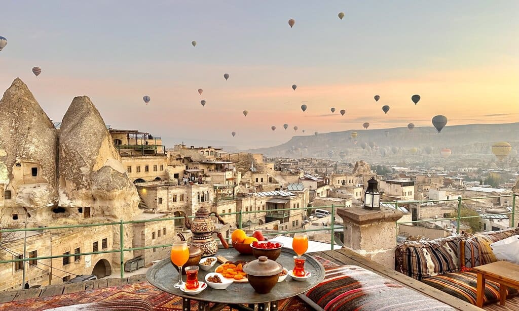 Sultan Cave Suites in Cappadocia at sunrise with balloons flying