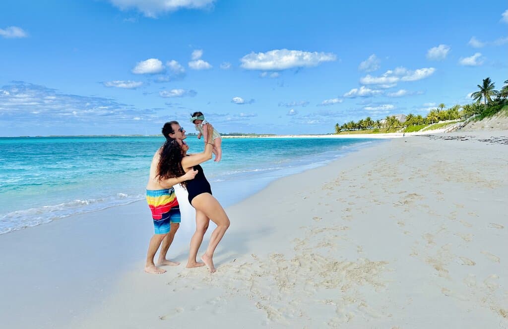 Chris Heckmann and Nimarta Bawa holding a baby in The Bahamas