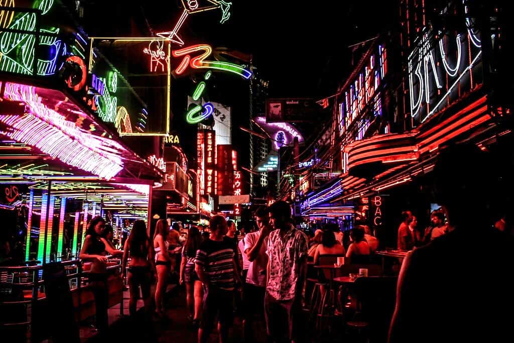 a red light district in Bangkok with girls in front of bars and men walking the street