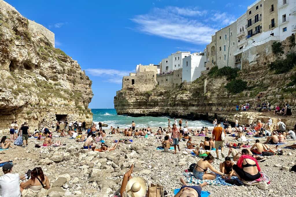 a view from the beach at Lama Monachile in Puglia with the cliffs on both sides and a lot of people on the beach