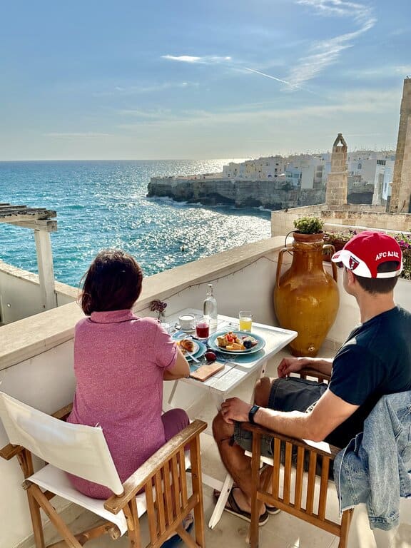 Chris Heckmann and Nimarta Bawa on top of a roof in Polignano a Mare looking at the coast